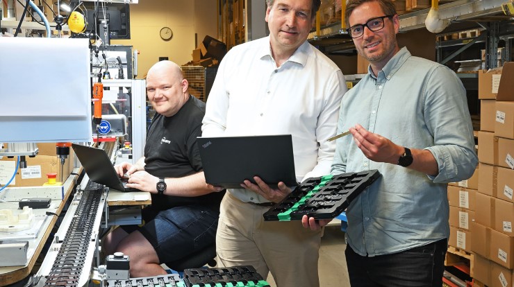 3 men, facing the camera and smiling, work together in TYRI's new circuit board factory in Sweden.